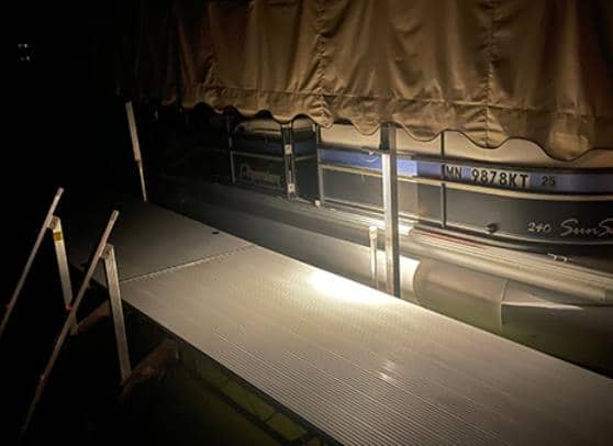 A pontoon boat featuring premium solar lights, with a dock at night.